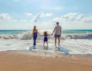 Family with little girl enjoying getting their feet wet in the sea